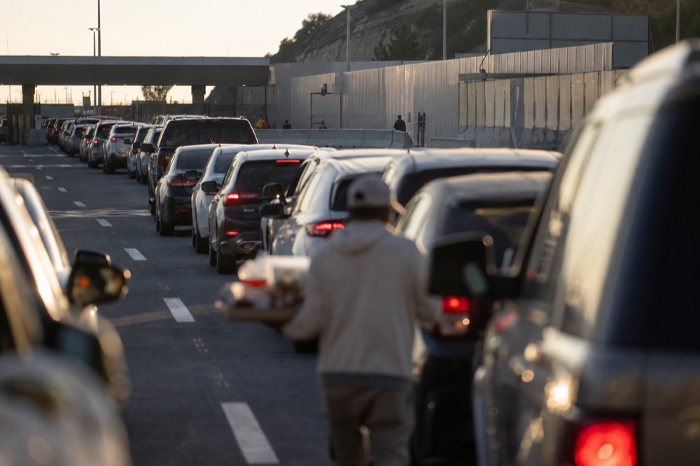 Lines of vehicles at a border crossing in late afternoon light, no text, no logos, no people