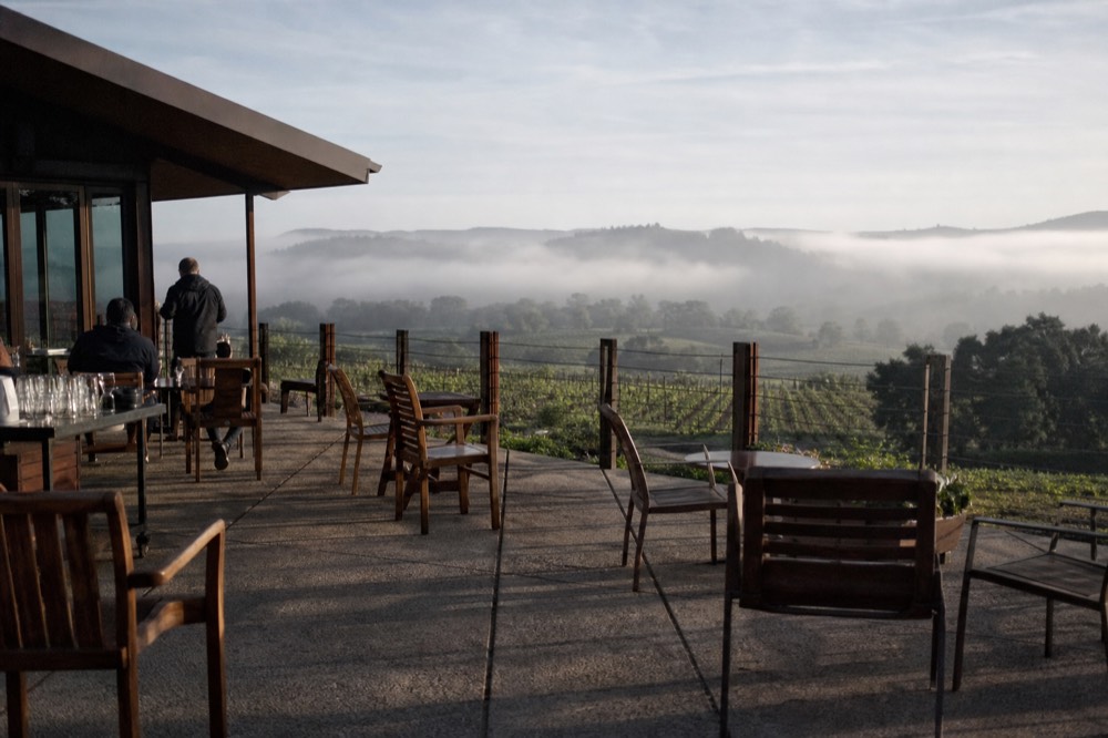A rustic winery tasting room terrace overlooking vineyard rows in Valle de Guadalupe, no text, no logos, no people