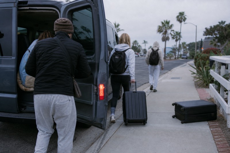 Travelers loading bags into a van on a San Diego street in the early morning