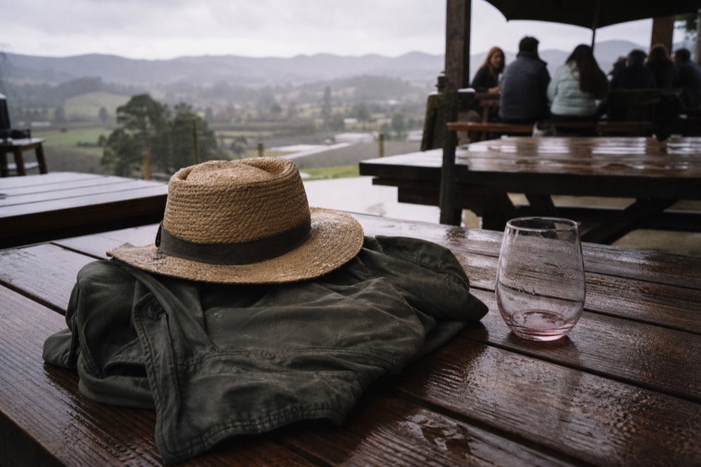 A folded jacket and sun hat resting on a wooden tasting bench, no text, no logos, no people