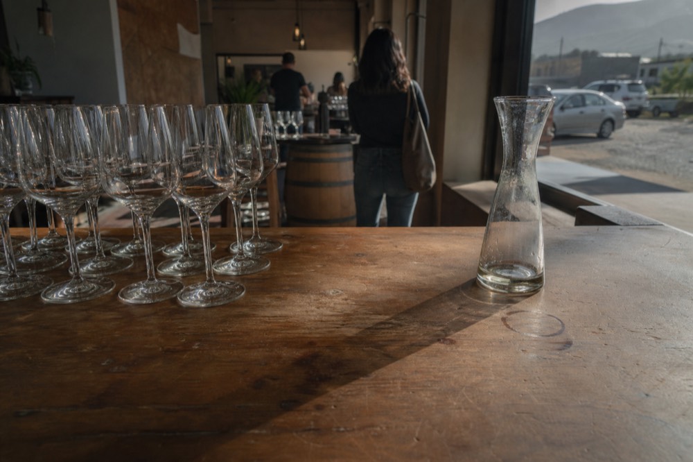 A tasting room counter with wine glasses arranged in a row, no text, no logos, no people.