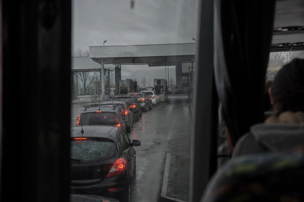 A border-crossing checkpoint queue seen from a tour vehicle window, no text, no logos, no people.