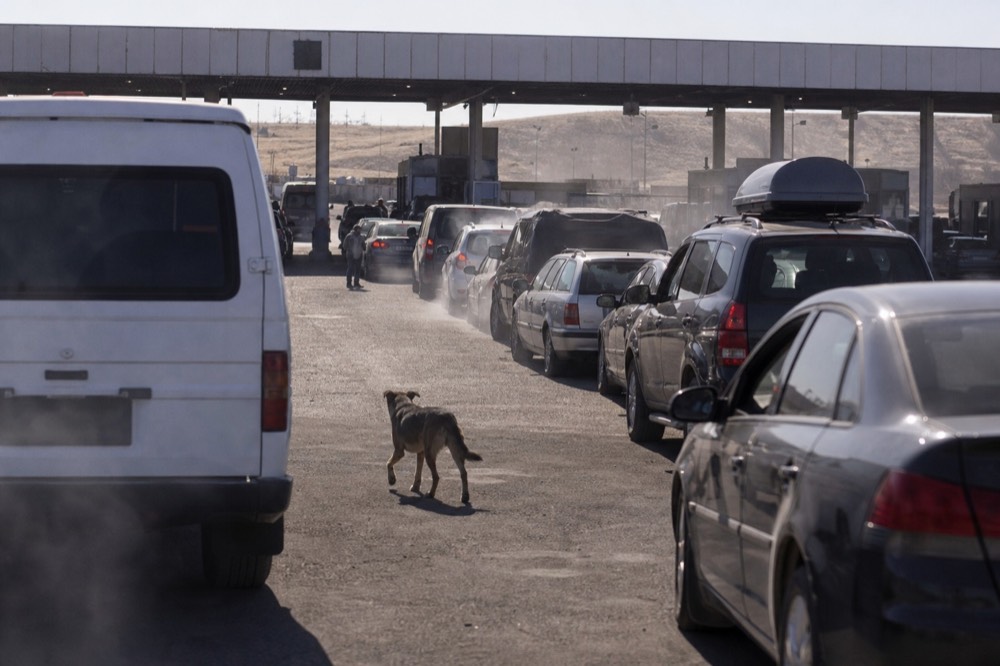 A border crossing checkpoint with vehicles waiting in line under daylight, no text, no logos, no people.