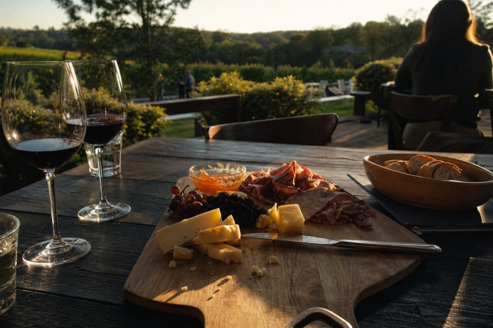 Cheese and charcuterie board served beside wine glasses at a Baja California winery, no text, no logos, no people