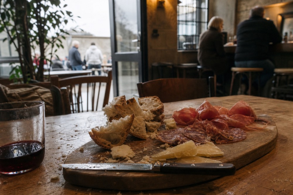 A wooden board of cured meats, cheese, and bread set on a tasting room table, no text, no logos, no people