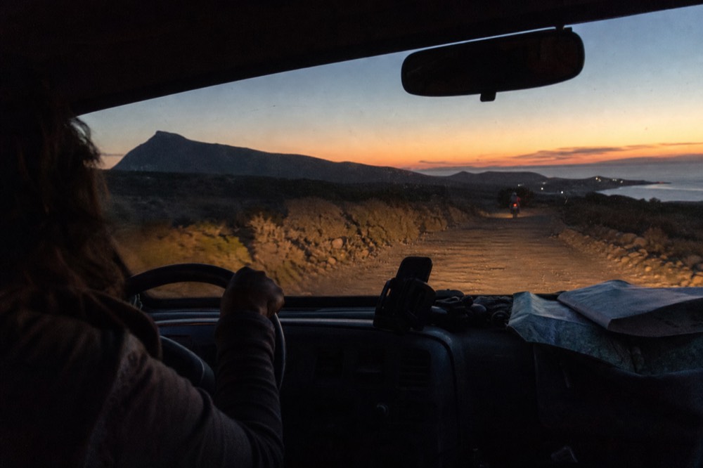 A driver's hands on the wheel of a van on a rural Baja road at dusk, no text, no logos, no people
